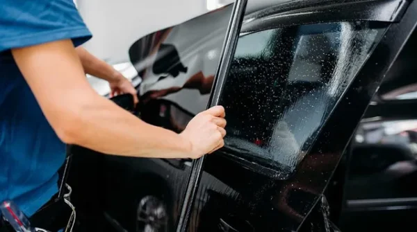 Applying 3M window film to car window for UV protection and heat control