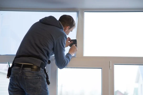 Technician applying home window tinting film to reduce heat and glare
