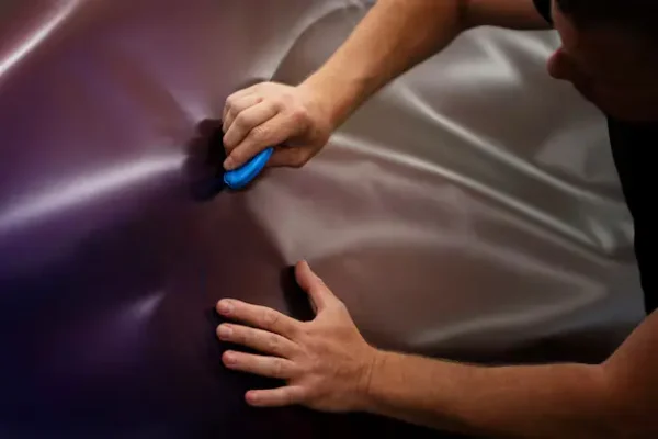 Applying paint protection film to a car surface to prevent scratches and maintain paint quality.