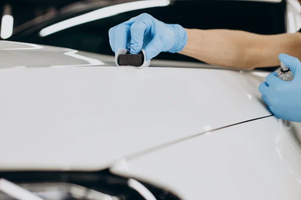 Technician applying ceramic paint protection to a white car for all-weather vehicle care