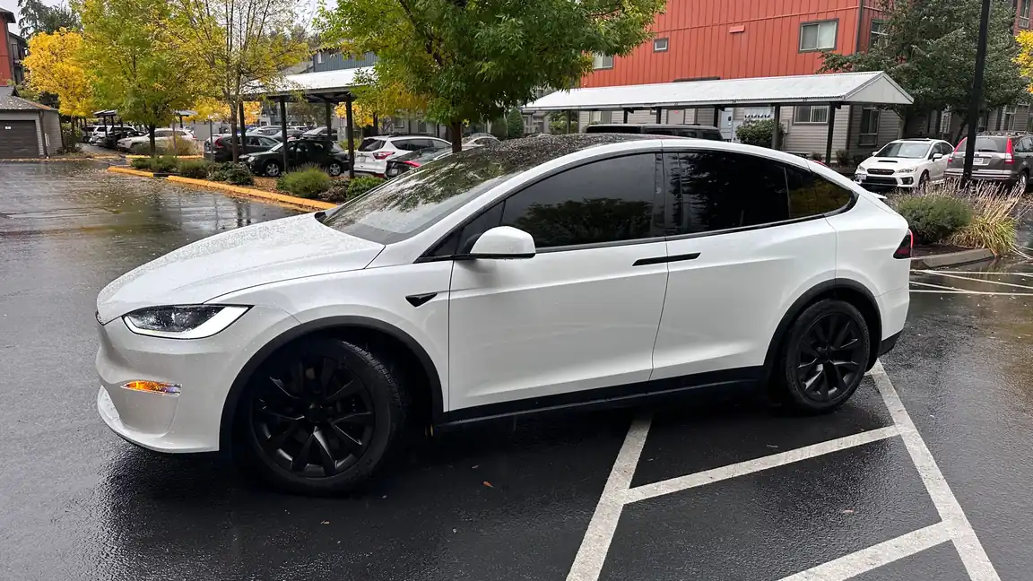 White Tesla Model X with professionally tinted windows parked outdoors in the rain