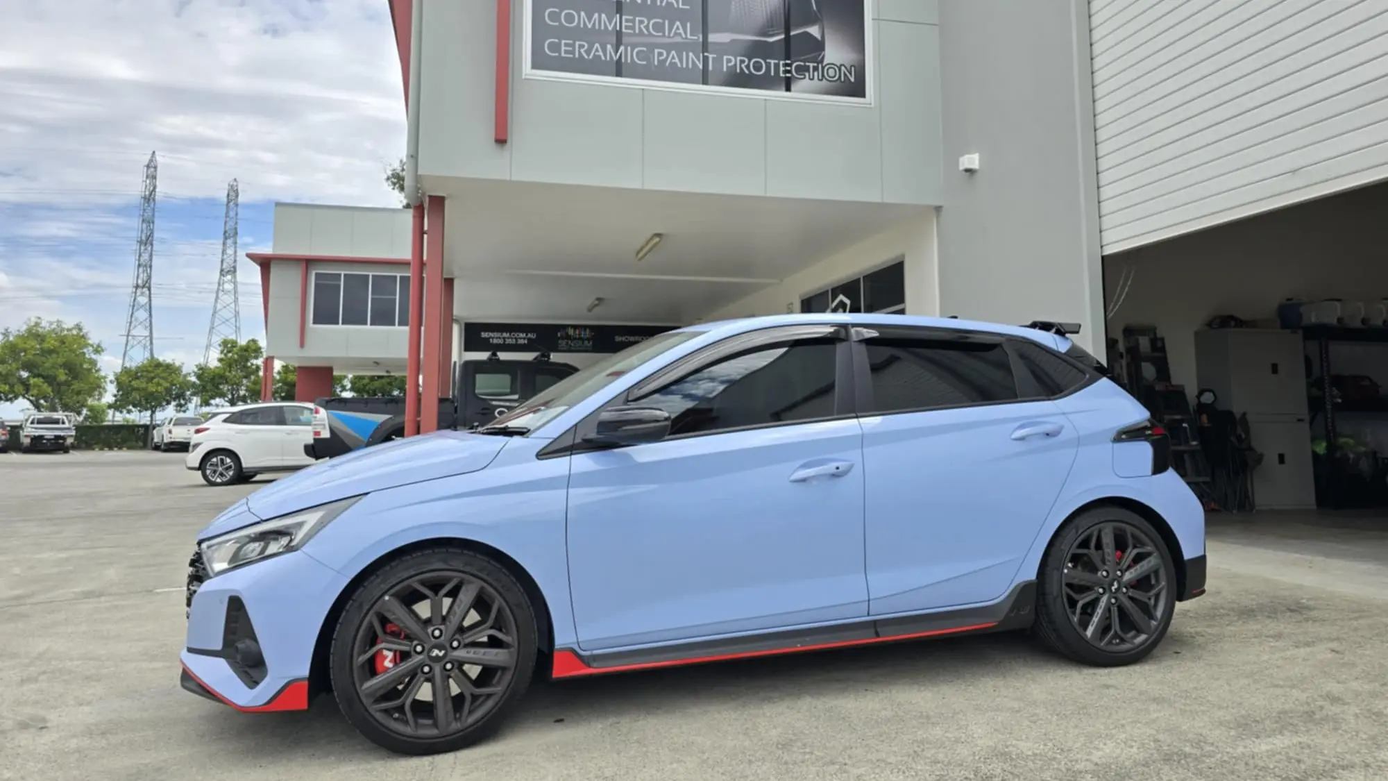 Blue Hyundai i20 N hatchback with dark car tint by GTS, parked in front of the Glass Tinting Solutions shop